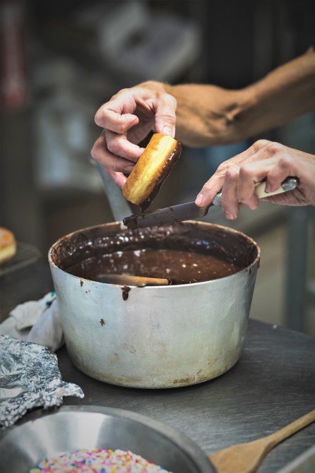 Donut Glazing by Hand: The hands of our legendary donut maker Johane at work! She makes, by hand, an average of 1,000 donuts per day.